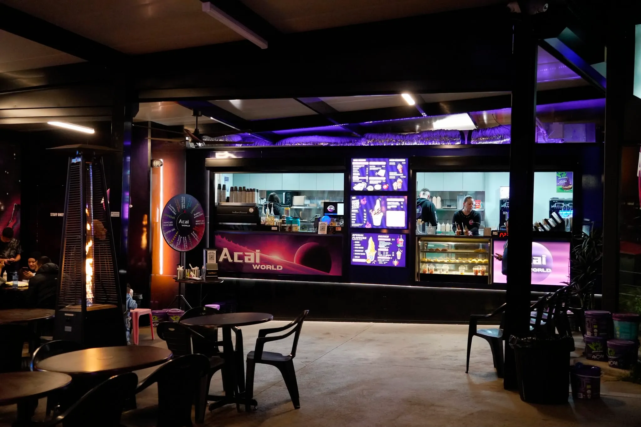 Açaí World storefront and outdoor seating lit up at night